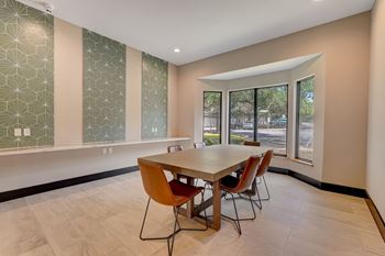 a dining room with a table and chairs and large windows